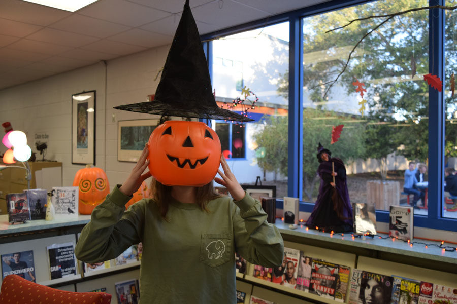 Tiffany Jette, 12th grade, has fun with decorations in the library for a spooky Halloween picture.