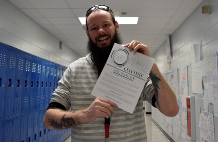 Mr. Sadler holds the entry form for the writing contest.