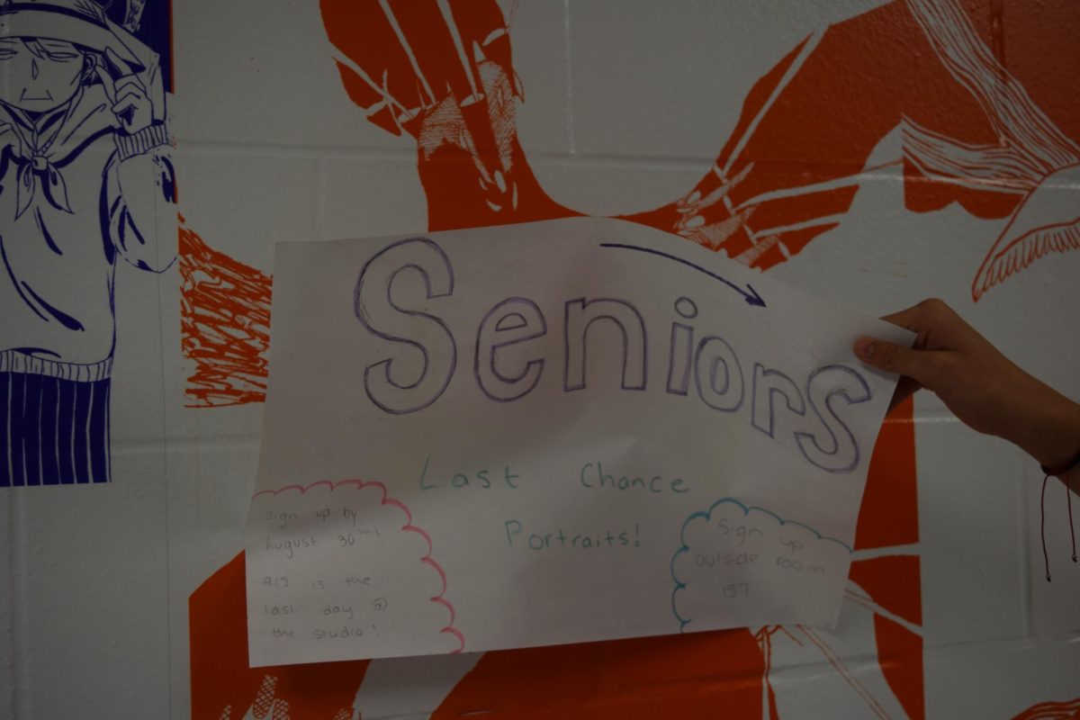 A student is taking down an old poster of the previous date.