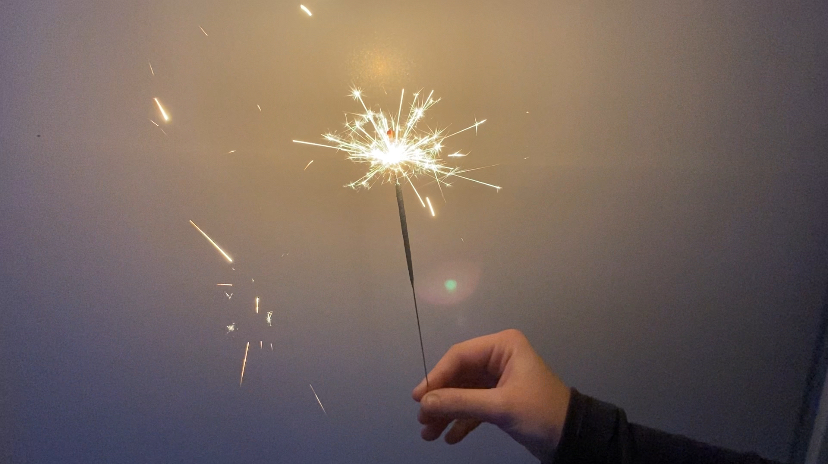 A+hand+holding+a+sparkler+on+New+Years+Eve+with+a+white+background.+