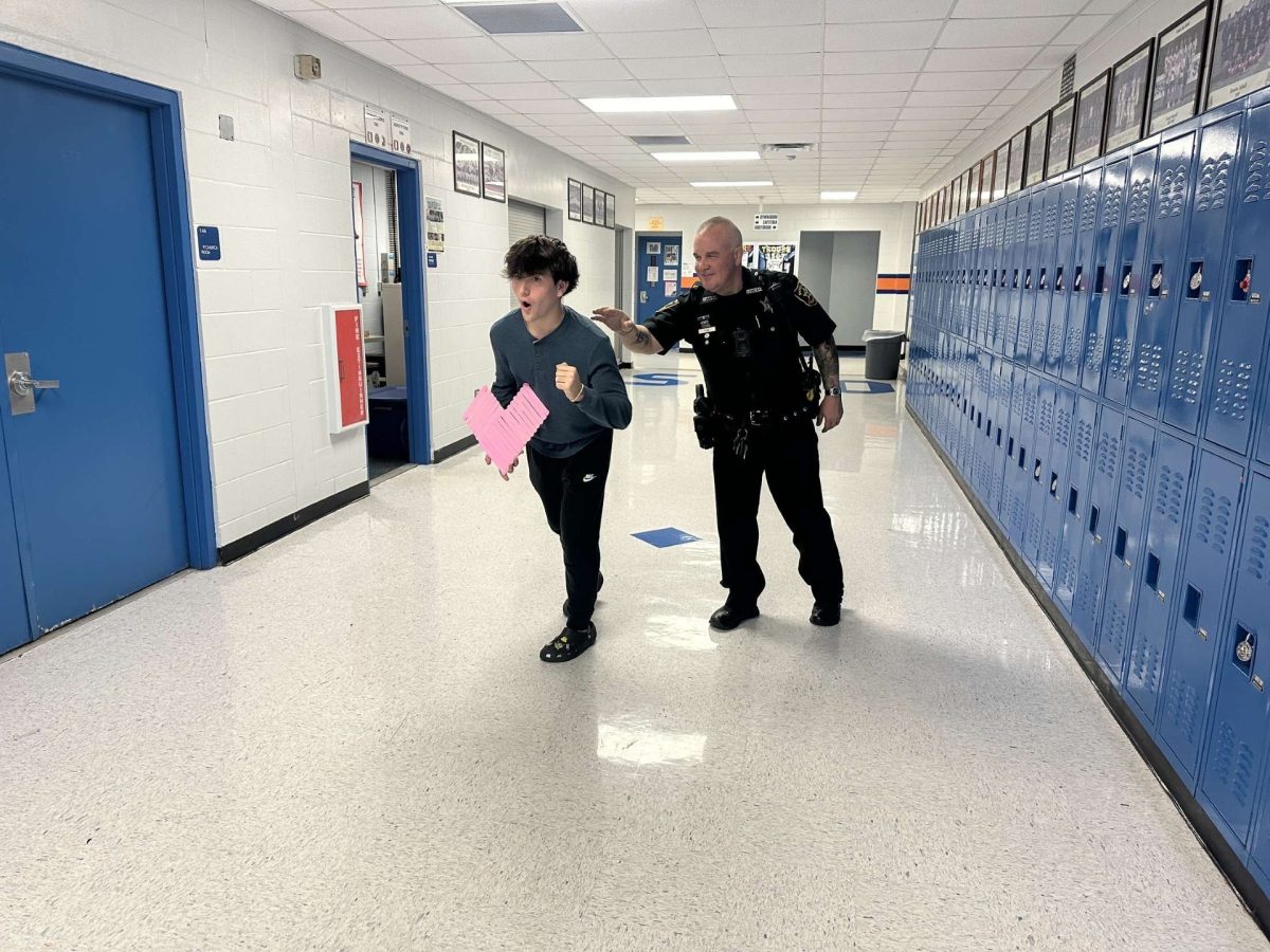 Student running from Deputy Funk with a heart for Valentines Day.