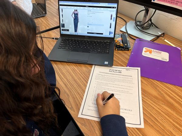 Student fills out Prom ticket form and looking at dresses.